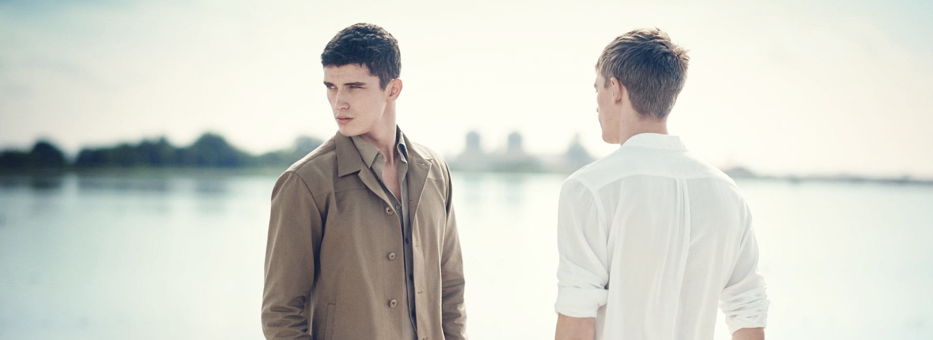 Two men facing away from each other looking into the distance.